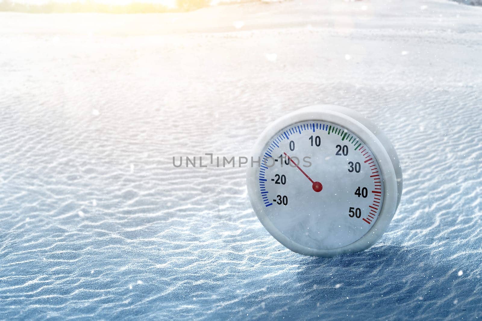 Thermometer with the low temperature at winter with snowfall background