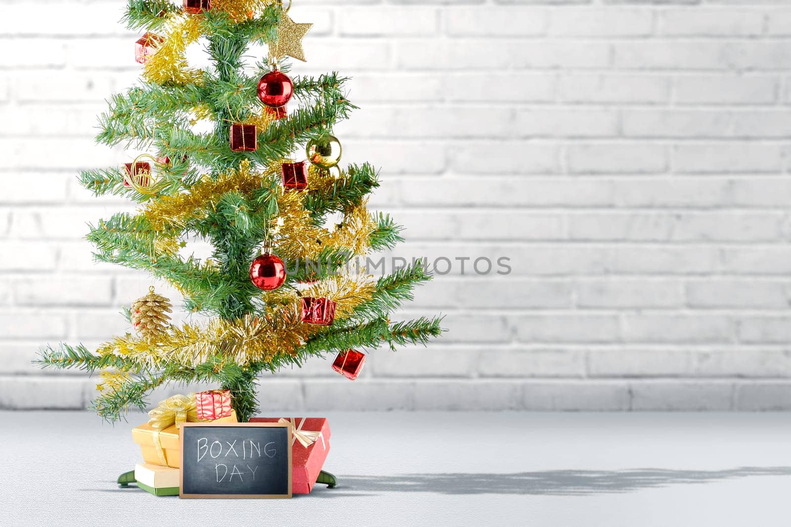 Christmas tree with gift box and Boxing Day text on the blackboard over brick wall background