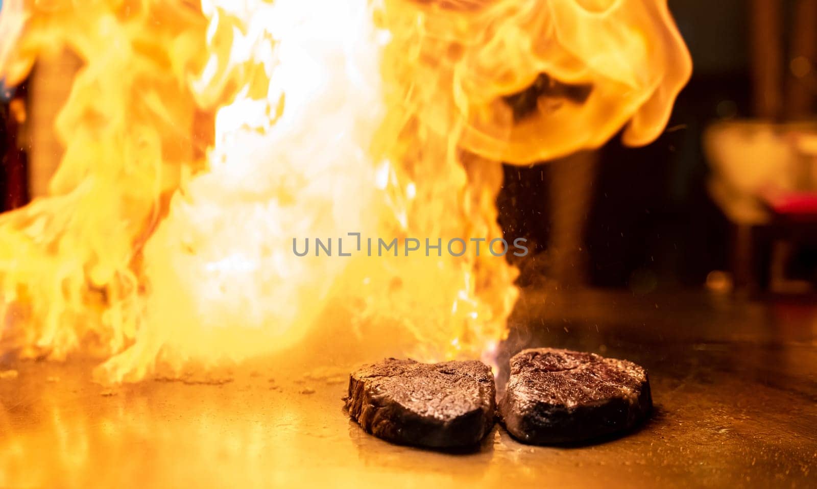 Cooking of beef teppanyaki recipe japanese grilled beef on cooking pan using scraper with flame in background