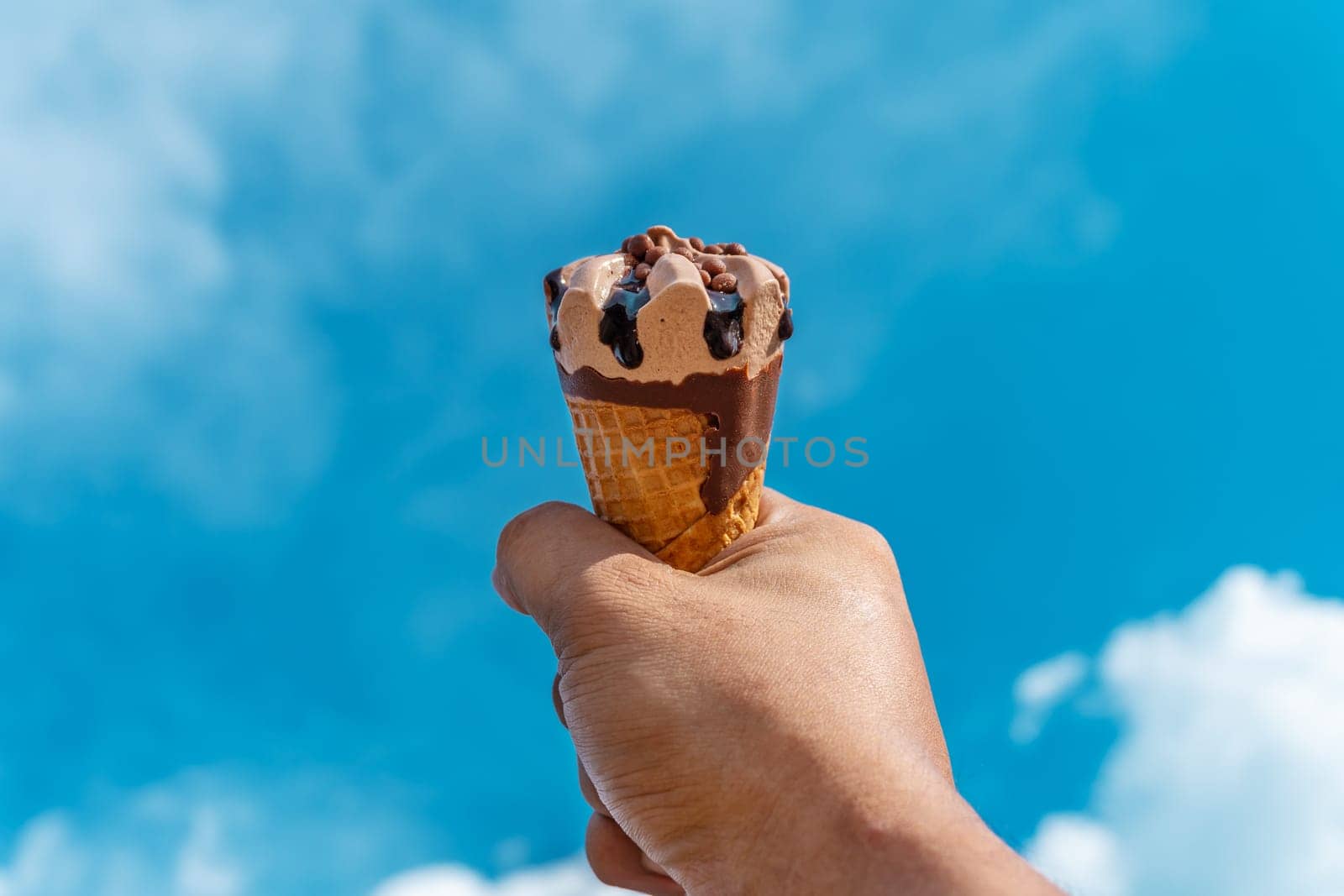Hand with ice cream on blurred blue sky nature background, Relaxation concept