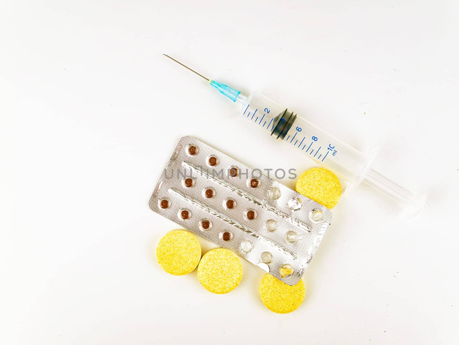 Medical syringe and pills on a white background.