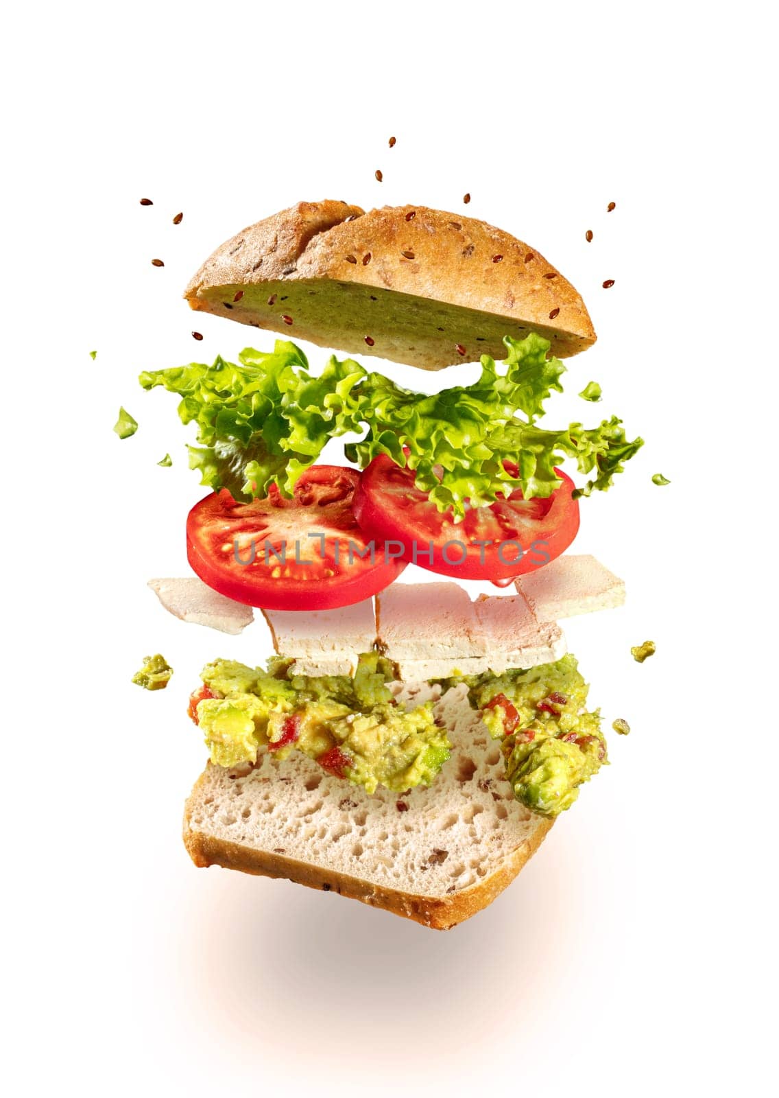 Exploded and flying vegetarian sandwich with guacamole and tofu cheese on white