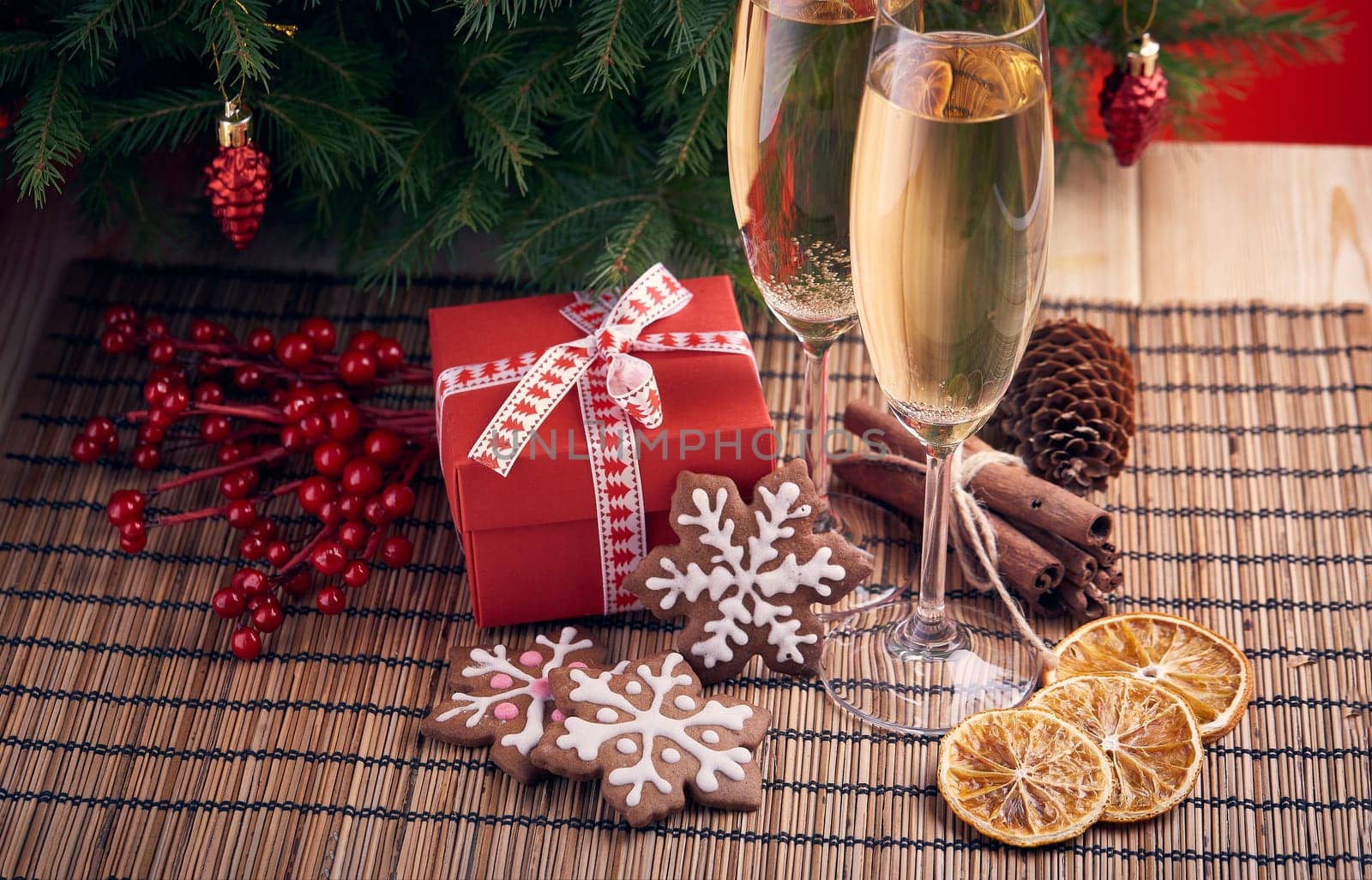 Two glasses with champange, gift boxes and christmas ginger cookies standing on a table near fir tree. New year and Christmas.