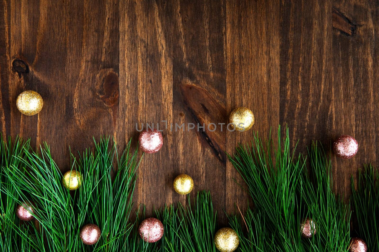 Pine boughs with christmas decorations on wooden surface with copy space.