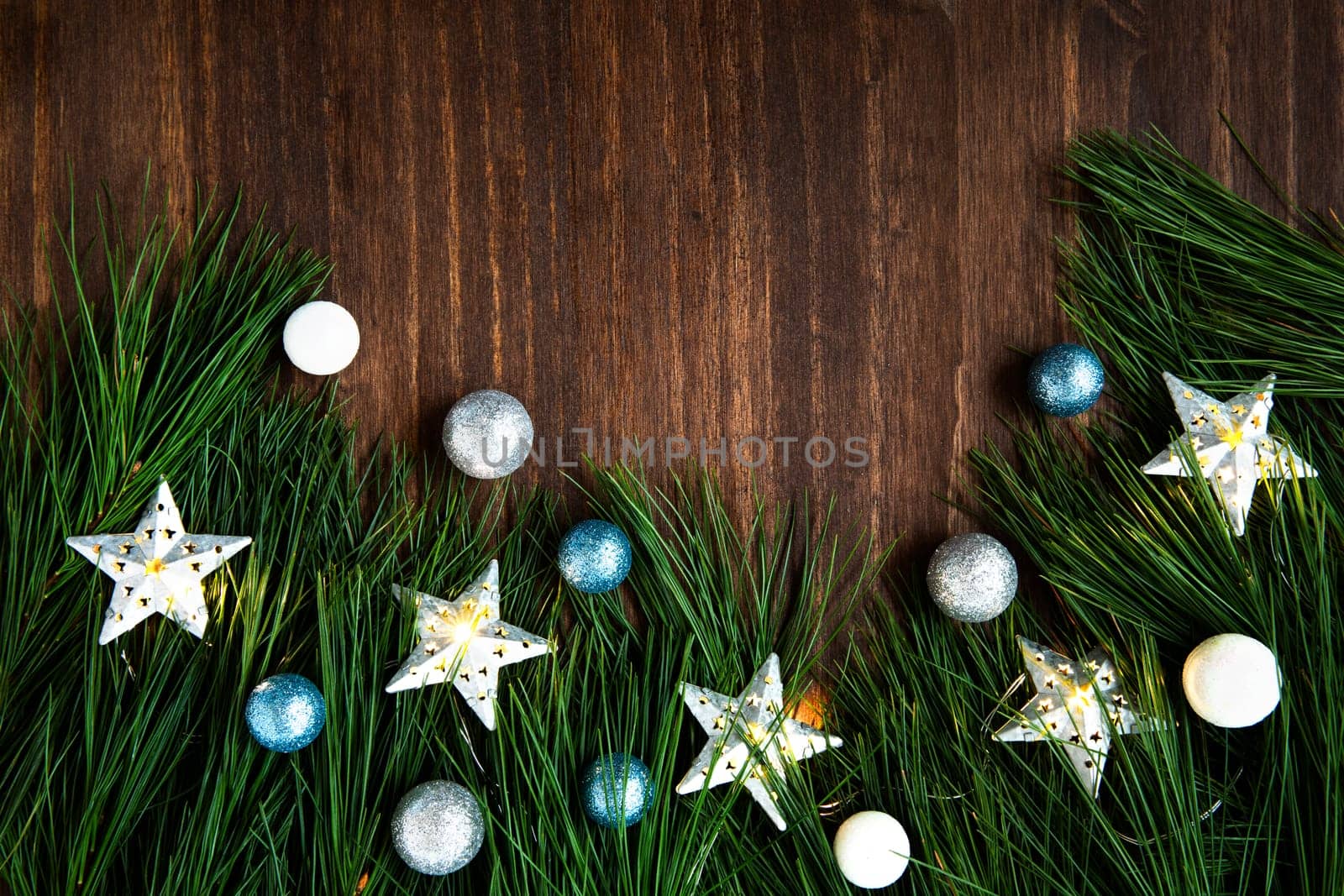 Pine boughs with christmas decorations on wooden surface with copy space.