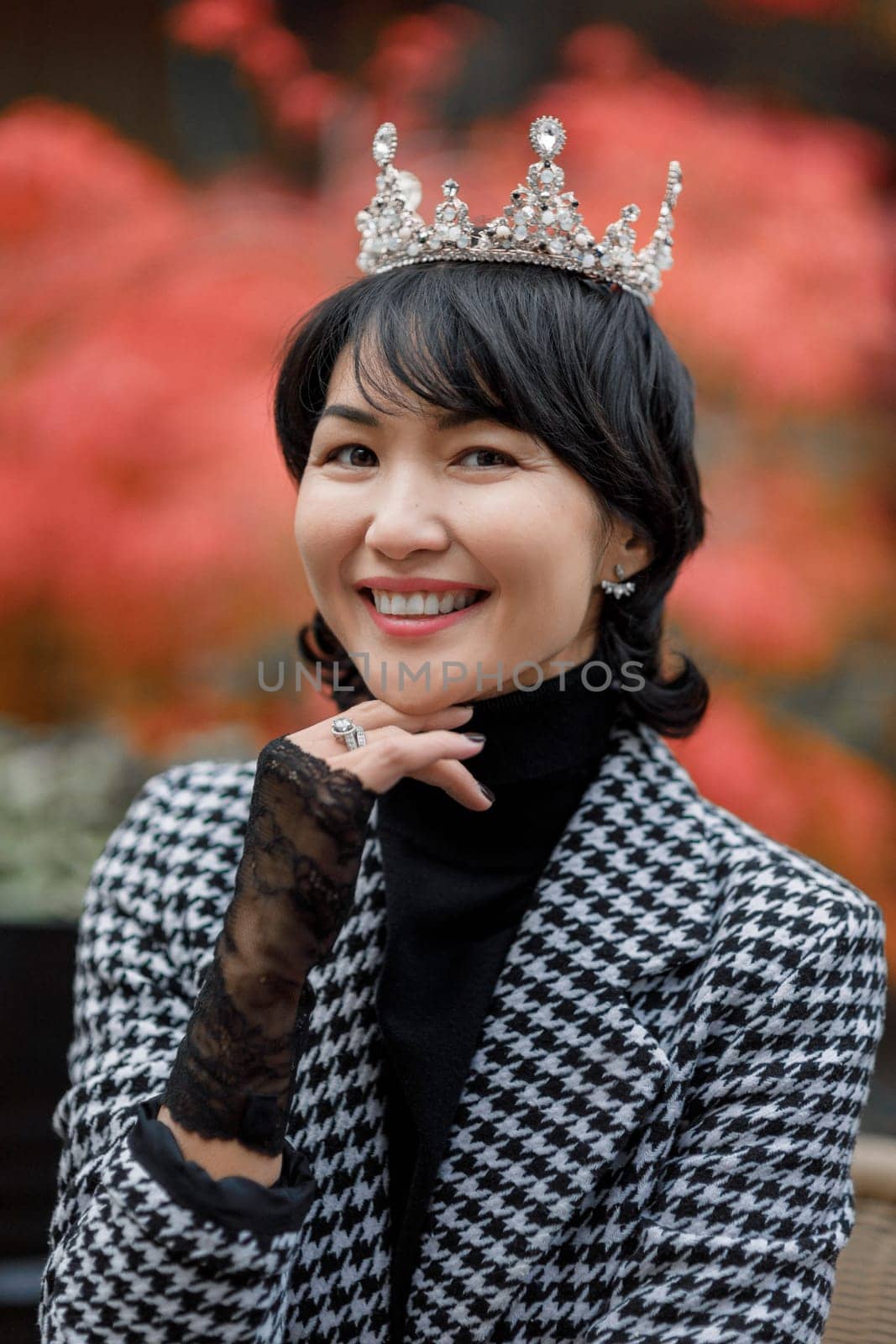 A girl of oriental nationality in a crown and fishnet gloves, laughing playfully