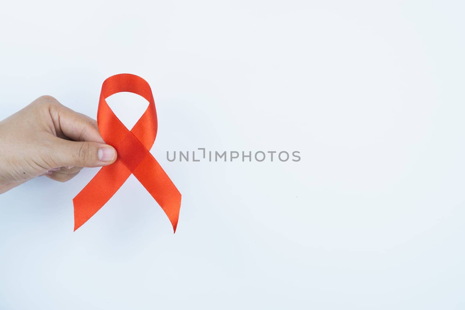 Aids awareness, male hands holding red AIDS awareness ribbon on white background. World Aids Day, Healthcare and medical concept.