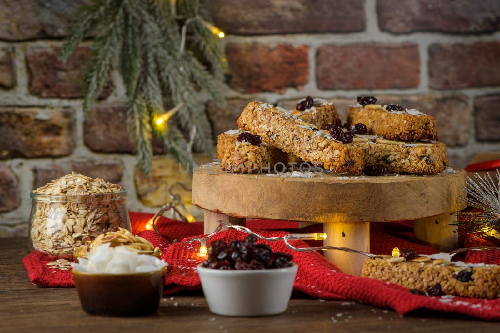 Cereal bars with almonds, coconut and cranberries on a Christmas season table decorated with lights.