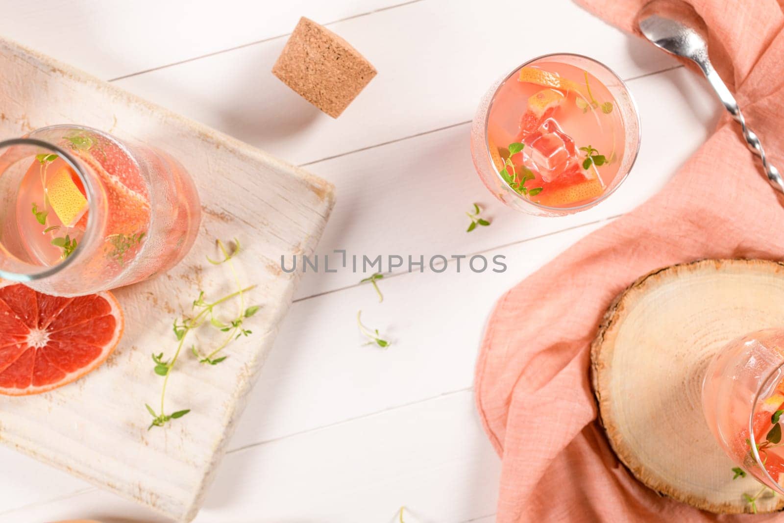Healthy summer drink grapefruit lemonade with thyme in glasses with ice on a wooden surface.