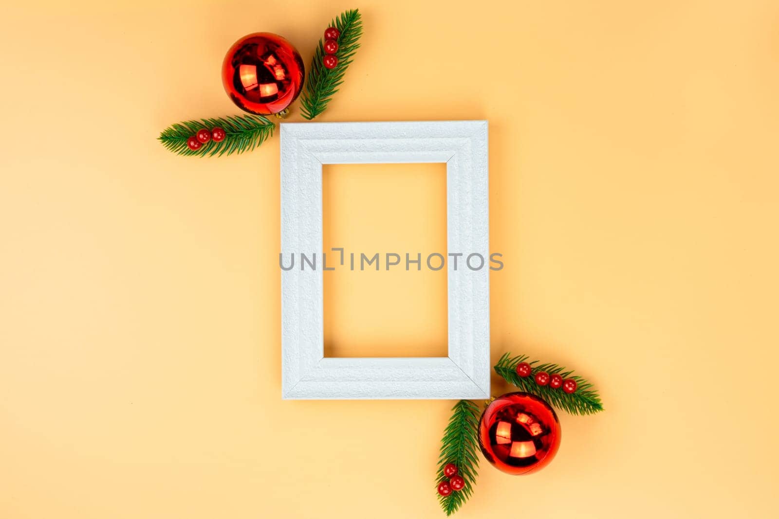 Christmas holidays composition, top view of red Christmas decorations and picture frame on yellow background with copy space for text. Flat lay, winter, postcard template, new year concept.