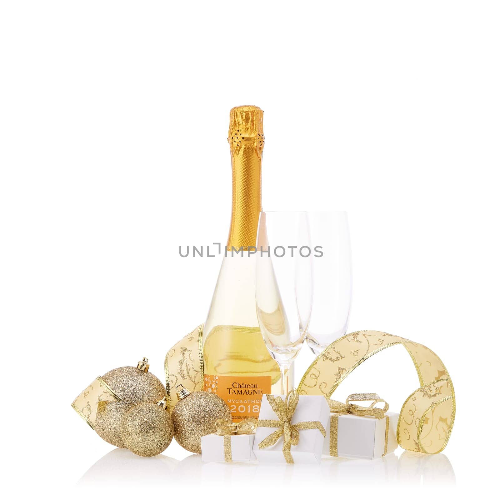 Bottle of muscat white young sparkling wine Chateau Tamagne 2018, gift boxes and Christmas ornaments isolated on a white background. New Year and Christmas