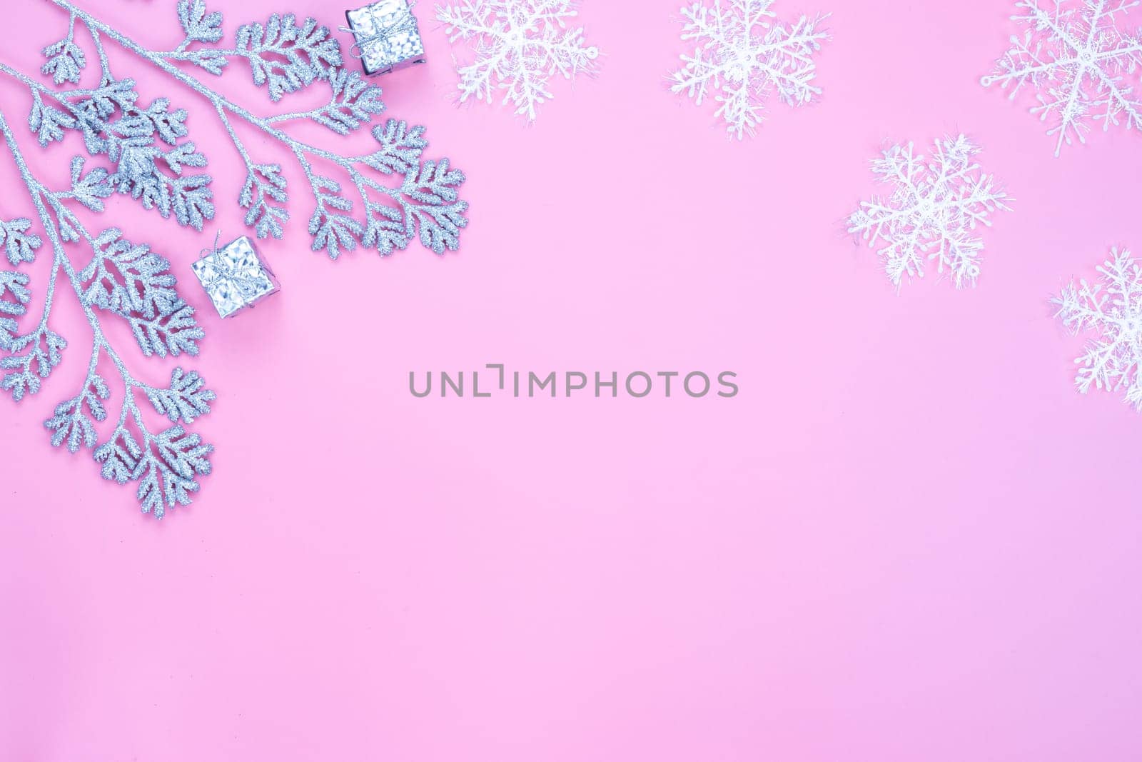 Christmas holidays composition, top view of silver Christmas decorations and snowflakes on pink background with copy space for text. Flat lay, winter, postcard template, new year concept.