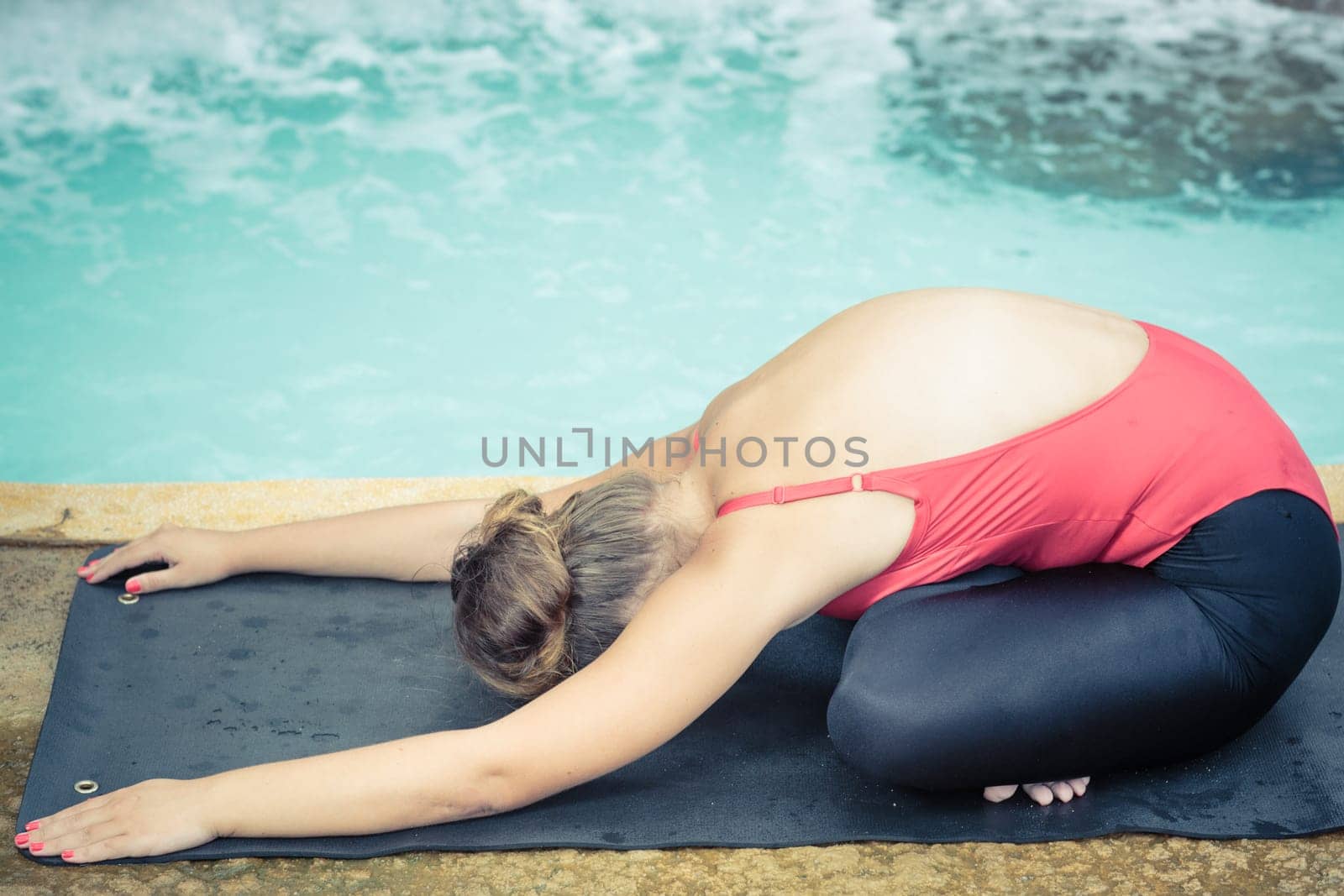 Woman practicing yoga near waterfall. Child Pose. Balasana