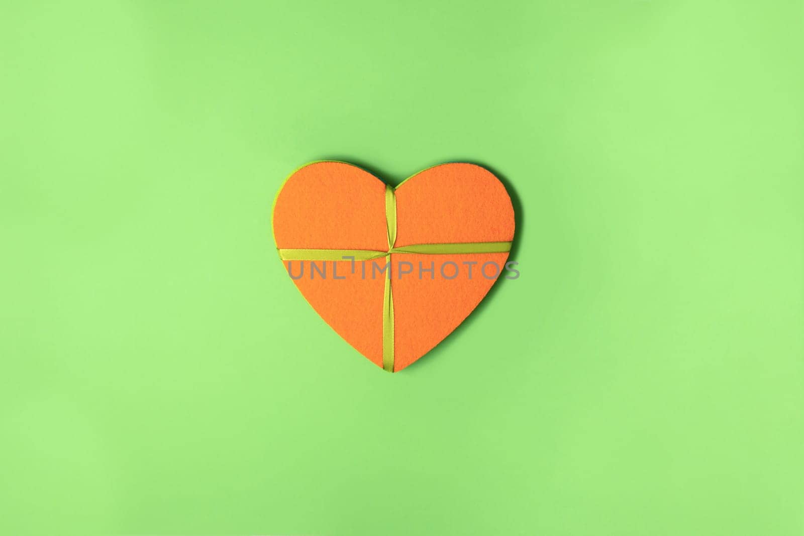 Orange felt heart with ribbon on green cardboard