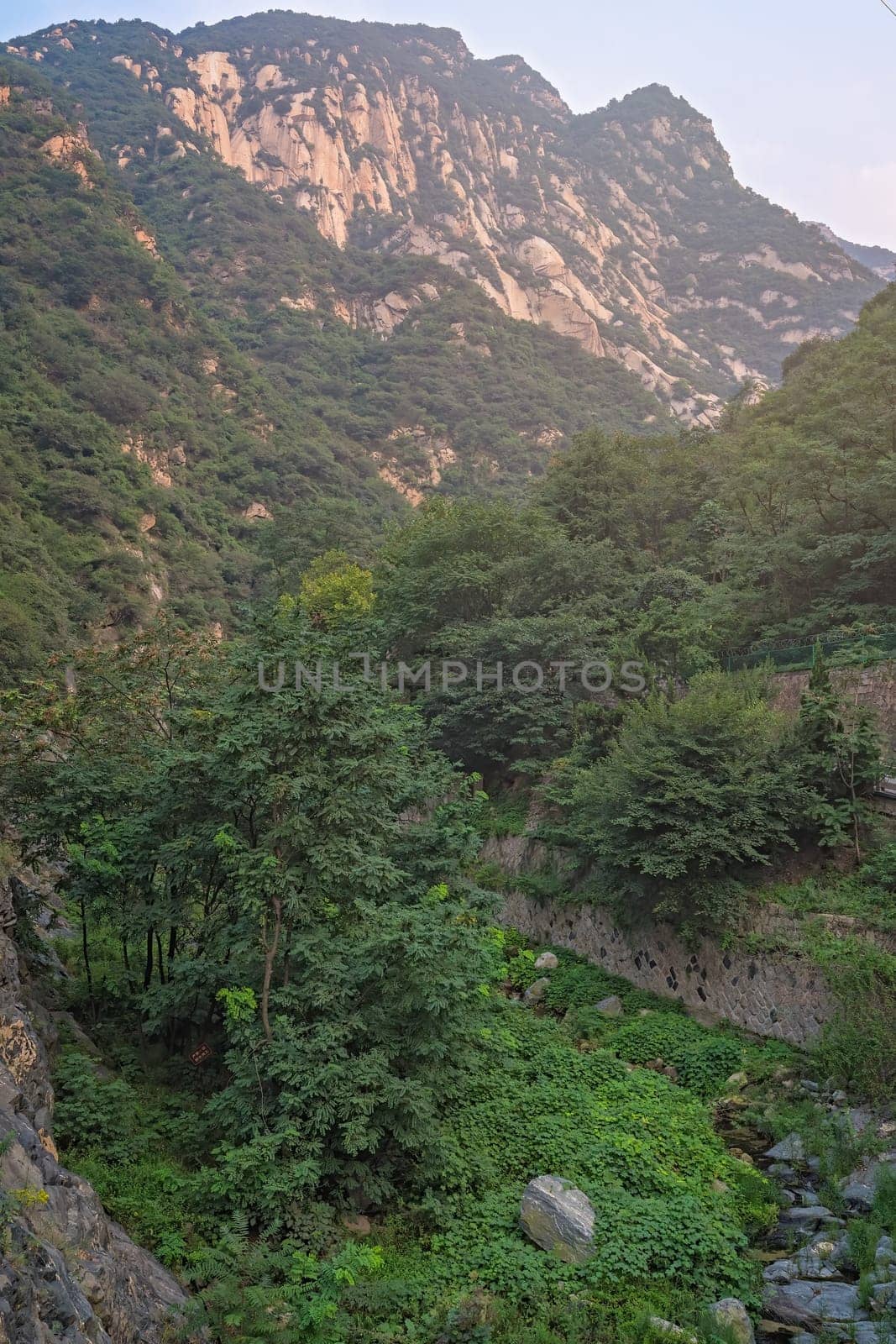 Stream flowing down in a narrow valley in front of the inspiring, sacred and majestic Huashan mountain, famous tourist attractions, Shaanxi province, China