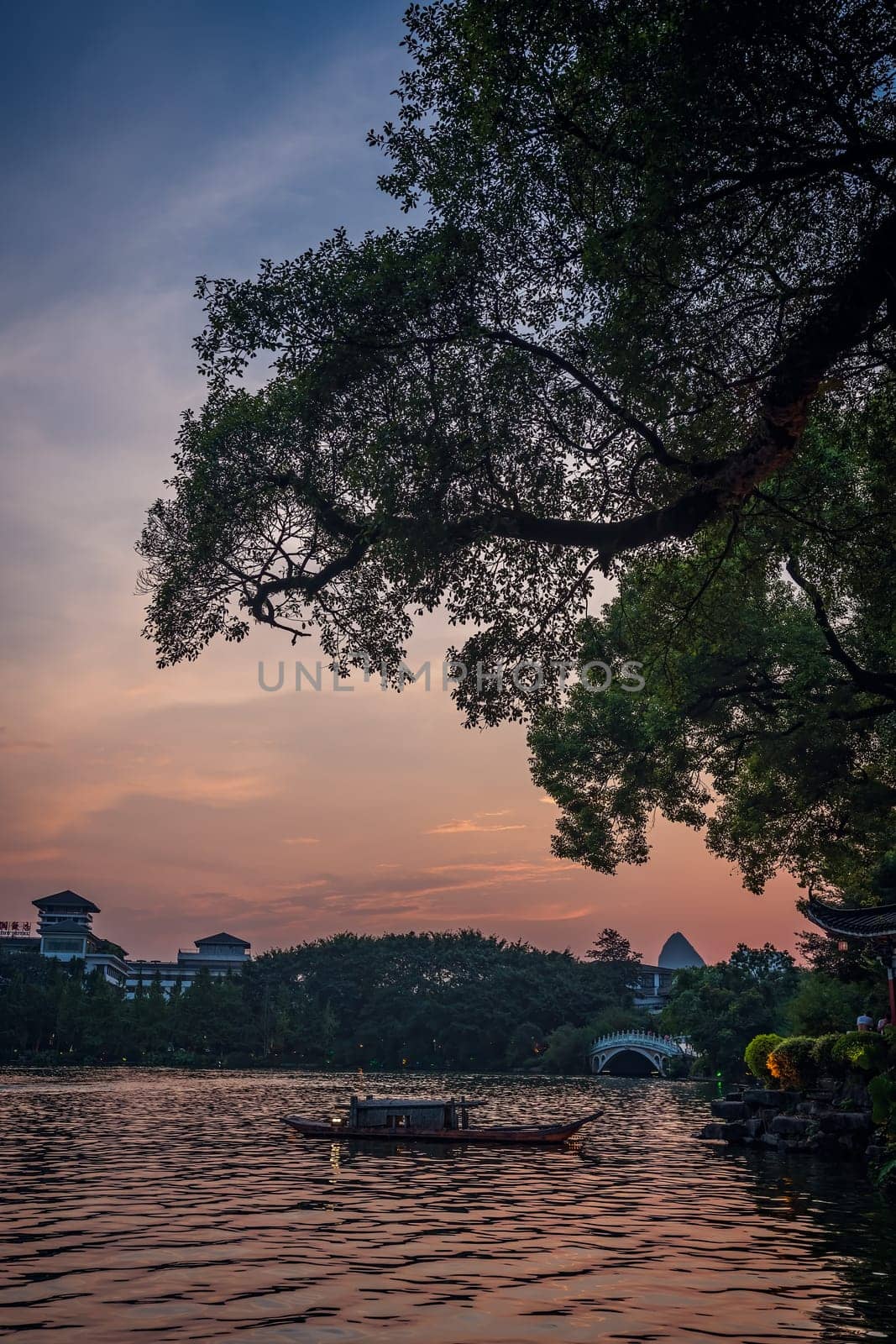 Small wooden boat on the waters of Shanhu or Shan Lake in Guilin town at sunset, Guangxi Province, China