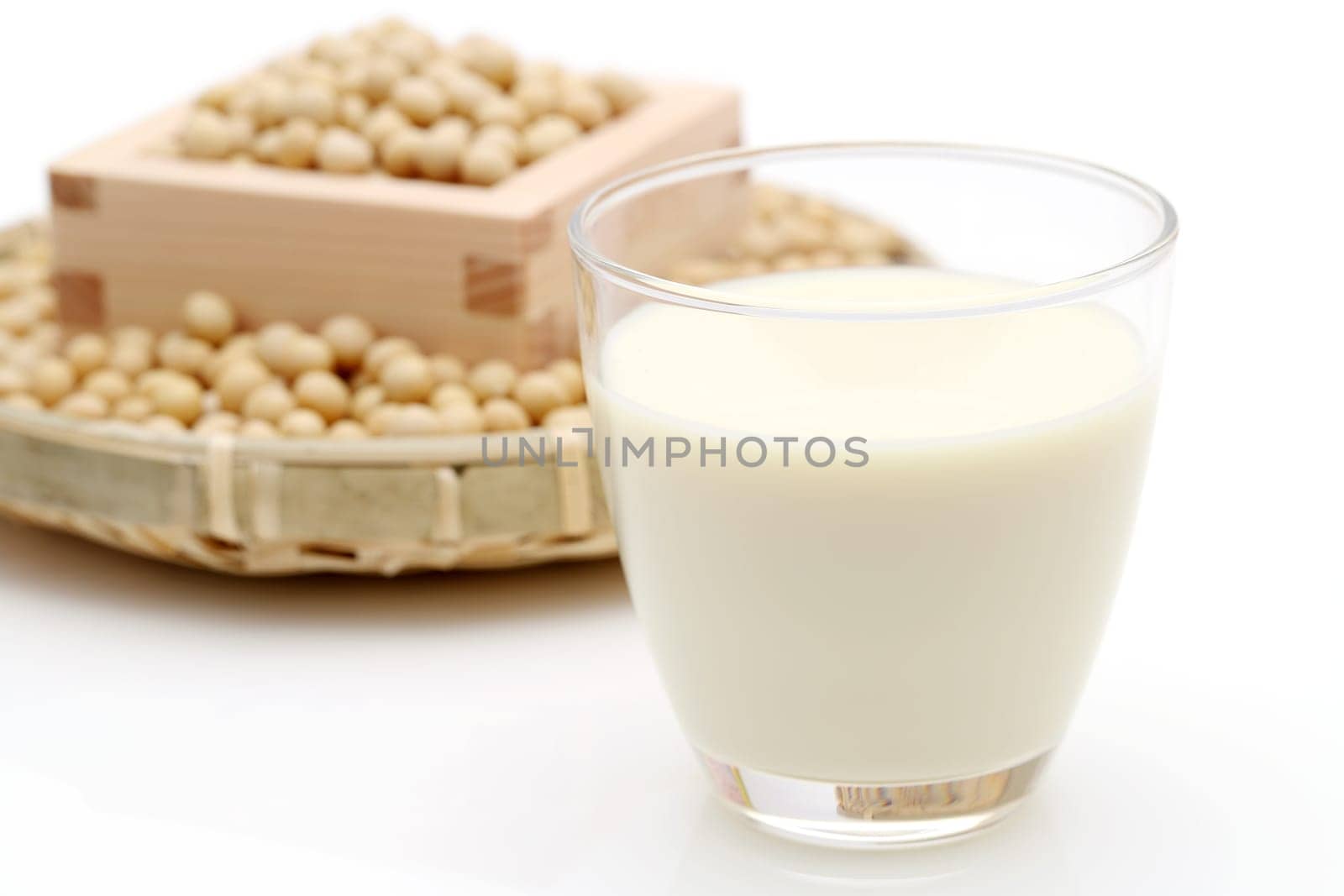 Glass of soy milk with soy bean on white background