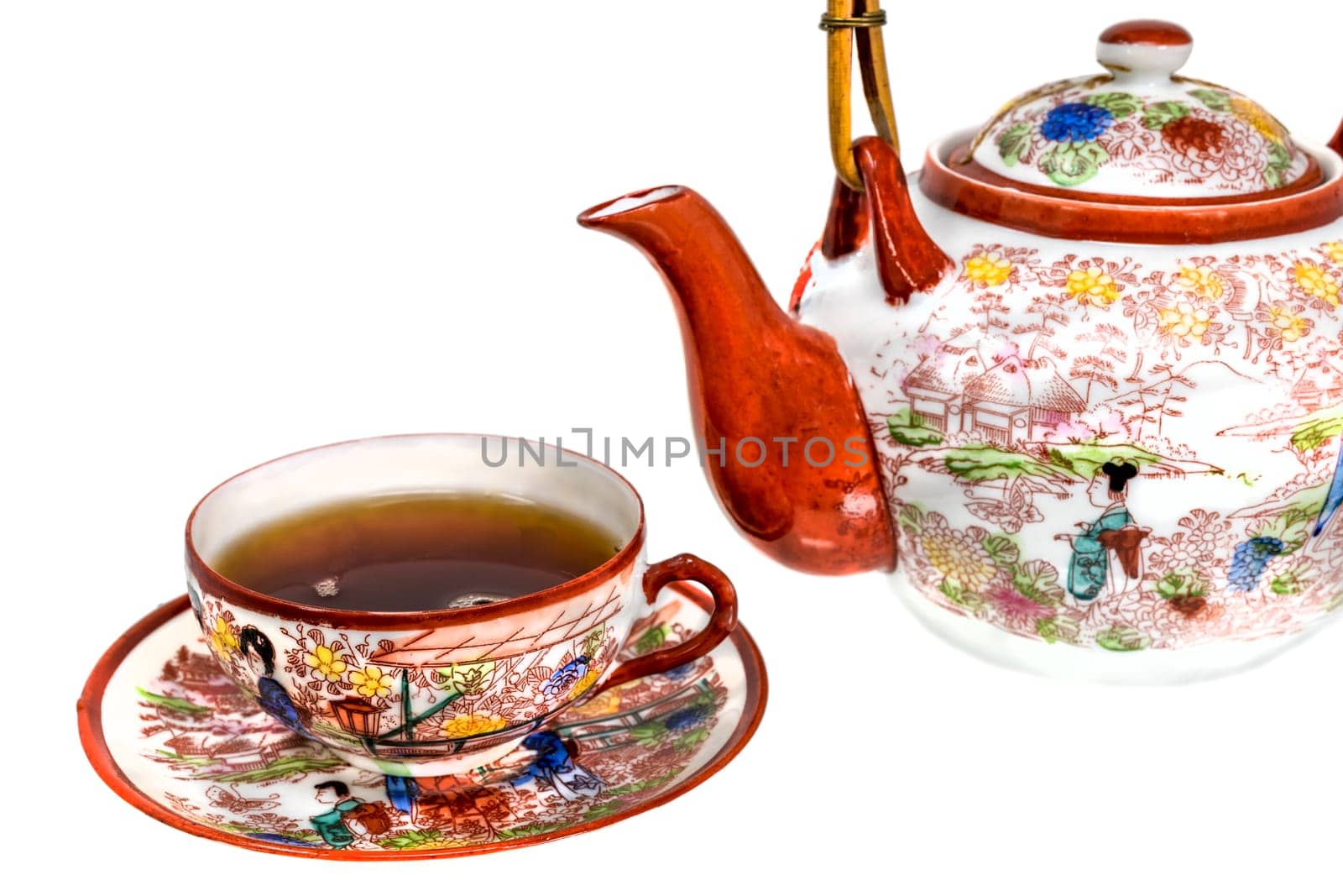 Tea cup filled with tea and teapot of painted Chinese porcelain isolated on white