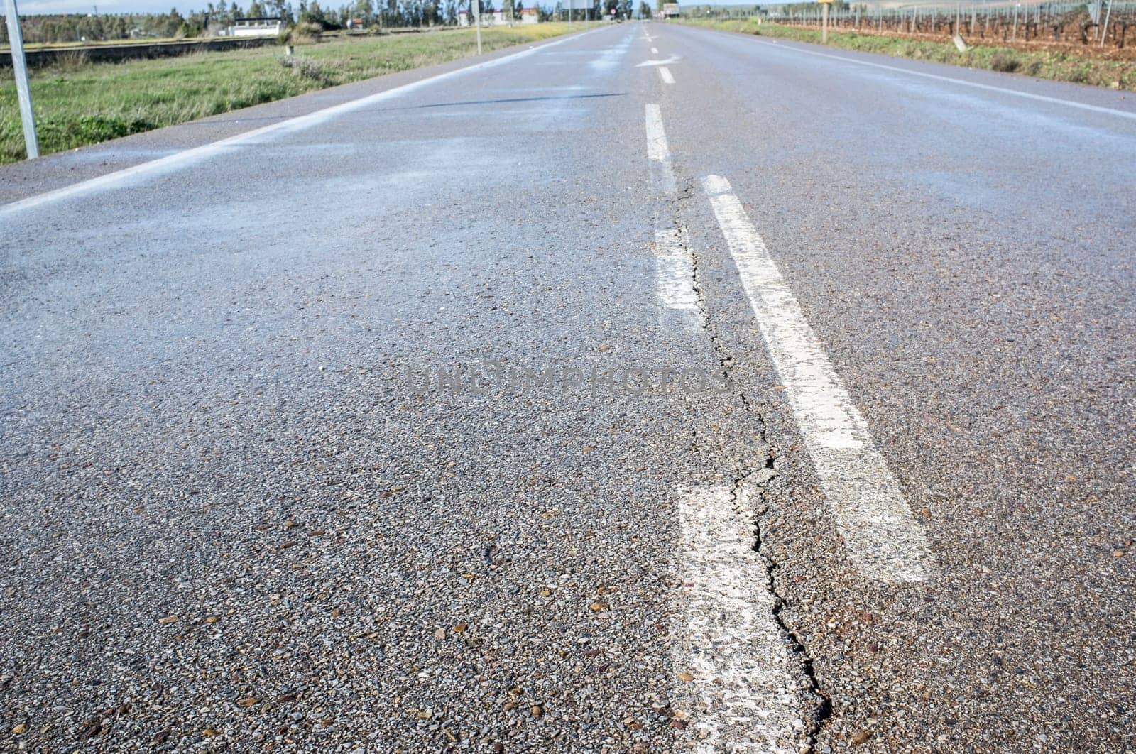 New road with cracked asphalt surface at country way. Deficient execution of civil construction concept