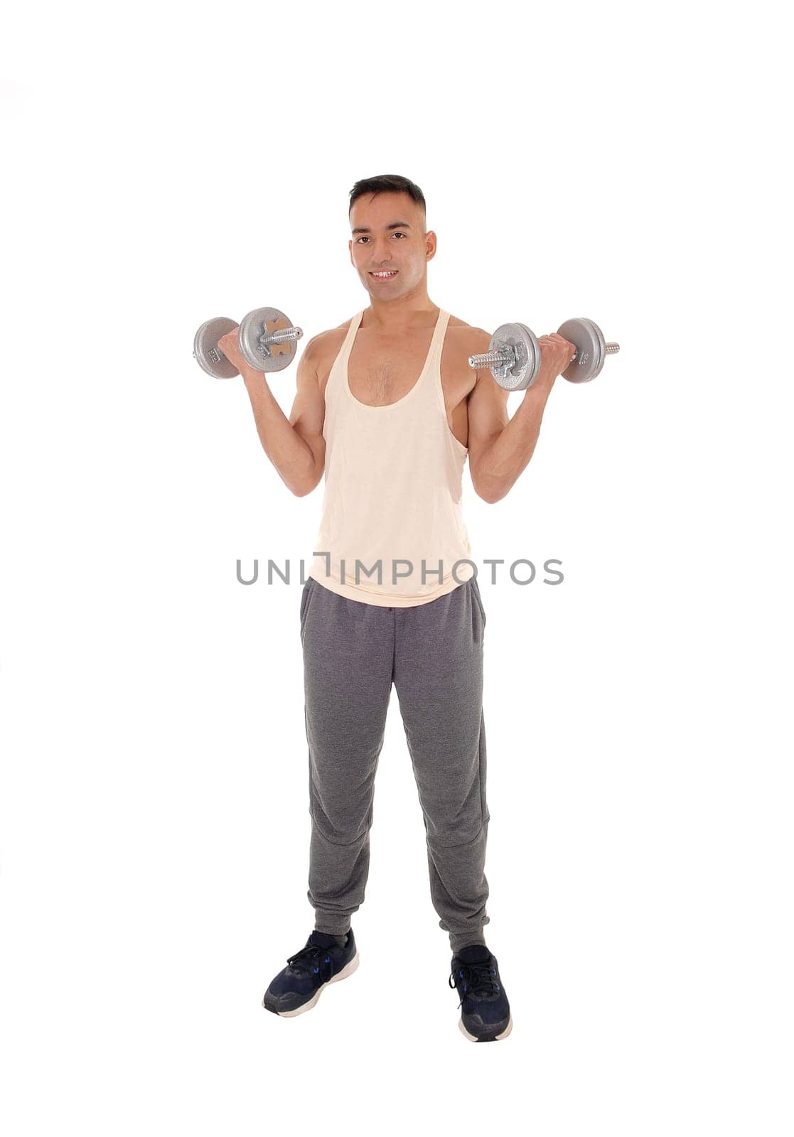 A east Indian man working out with two dumbbells in his.track pants, isolated for white background.