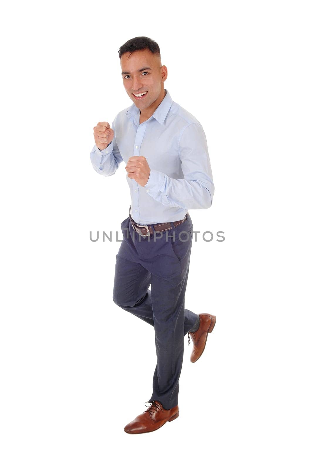 A handsome young man in a blue shirt and dress pants is running in.the studio, isolated for white background.