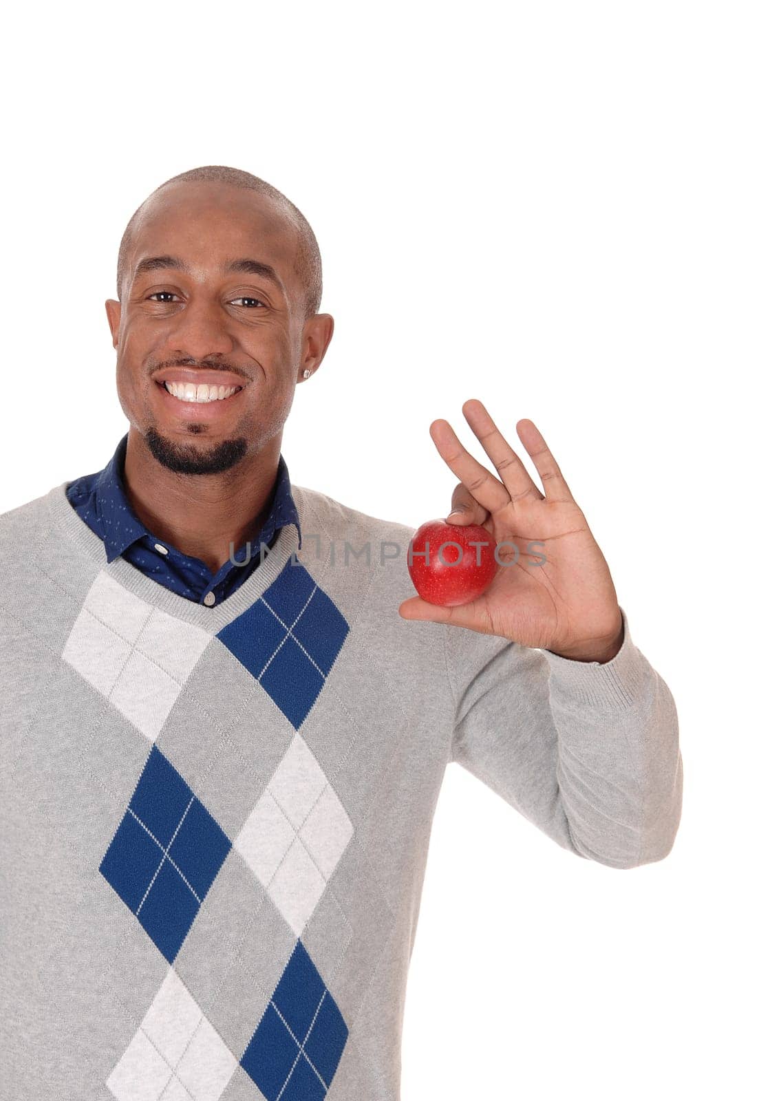 An African American man standing in a sweater, smiling bright and.holding in his hand a red apple, isolated for white background.