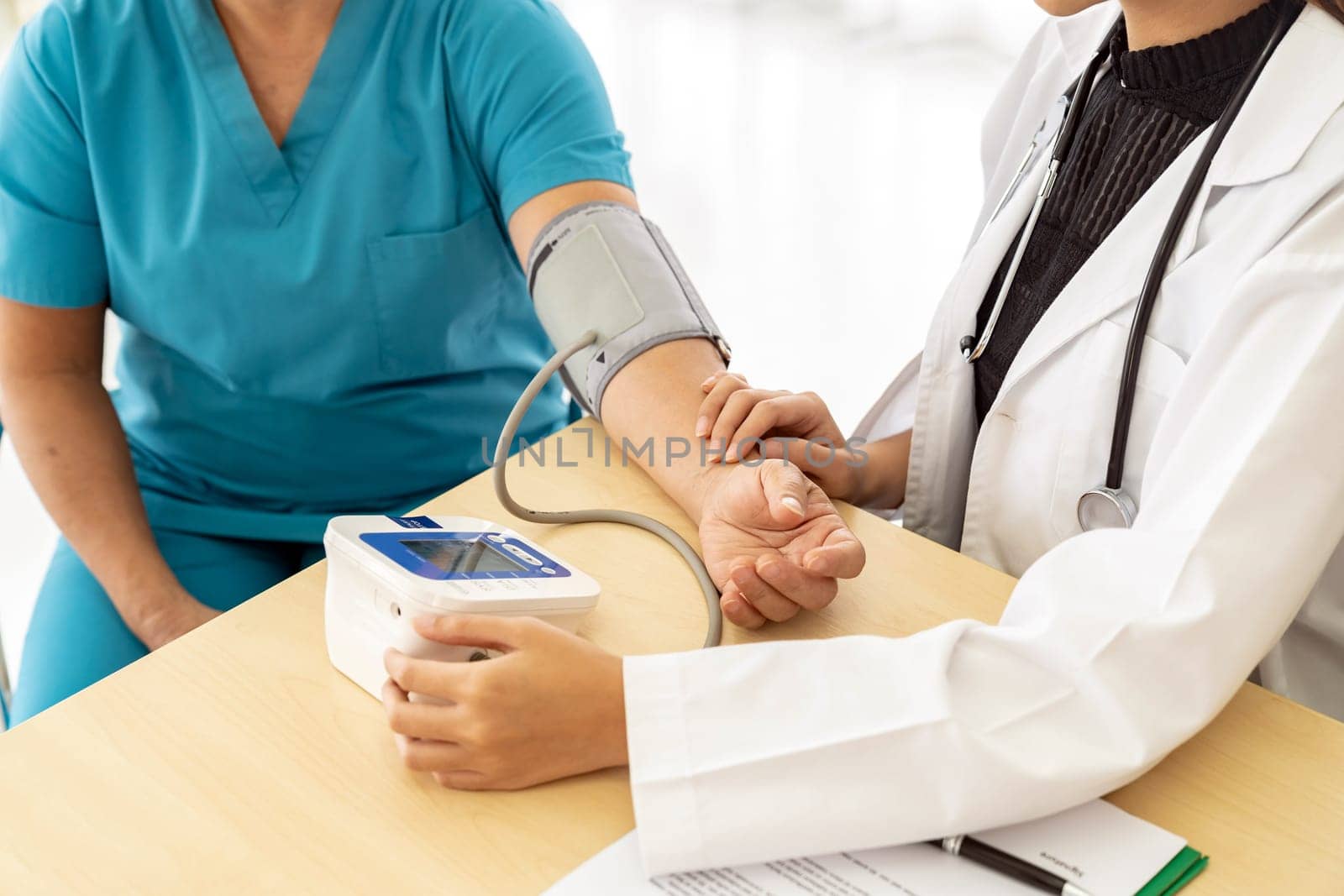 Female doctor measuring blood pressure of senior woman elderly at examination room in hospital clinic.