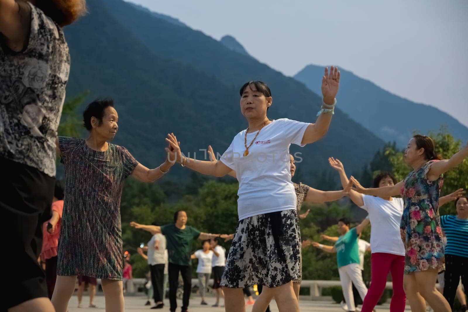 Huashan, China -  August 2019 : Group of Chinese women dancing in the open plaza square at the foot of HuaShan mountain at dusk, Shaanxi Province