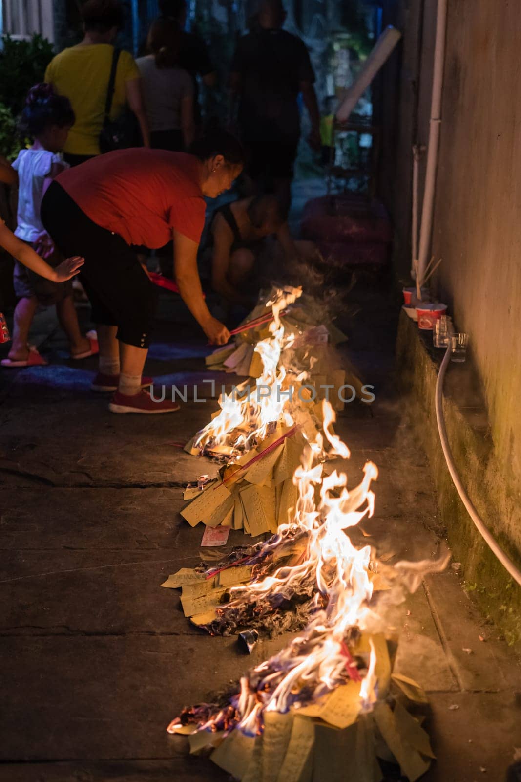 Feng Huang, China -  August 2019 : People burning paper on streets and pavements in a religious festival ceremony to pay respect to ancestors and spirits