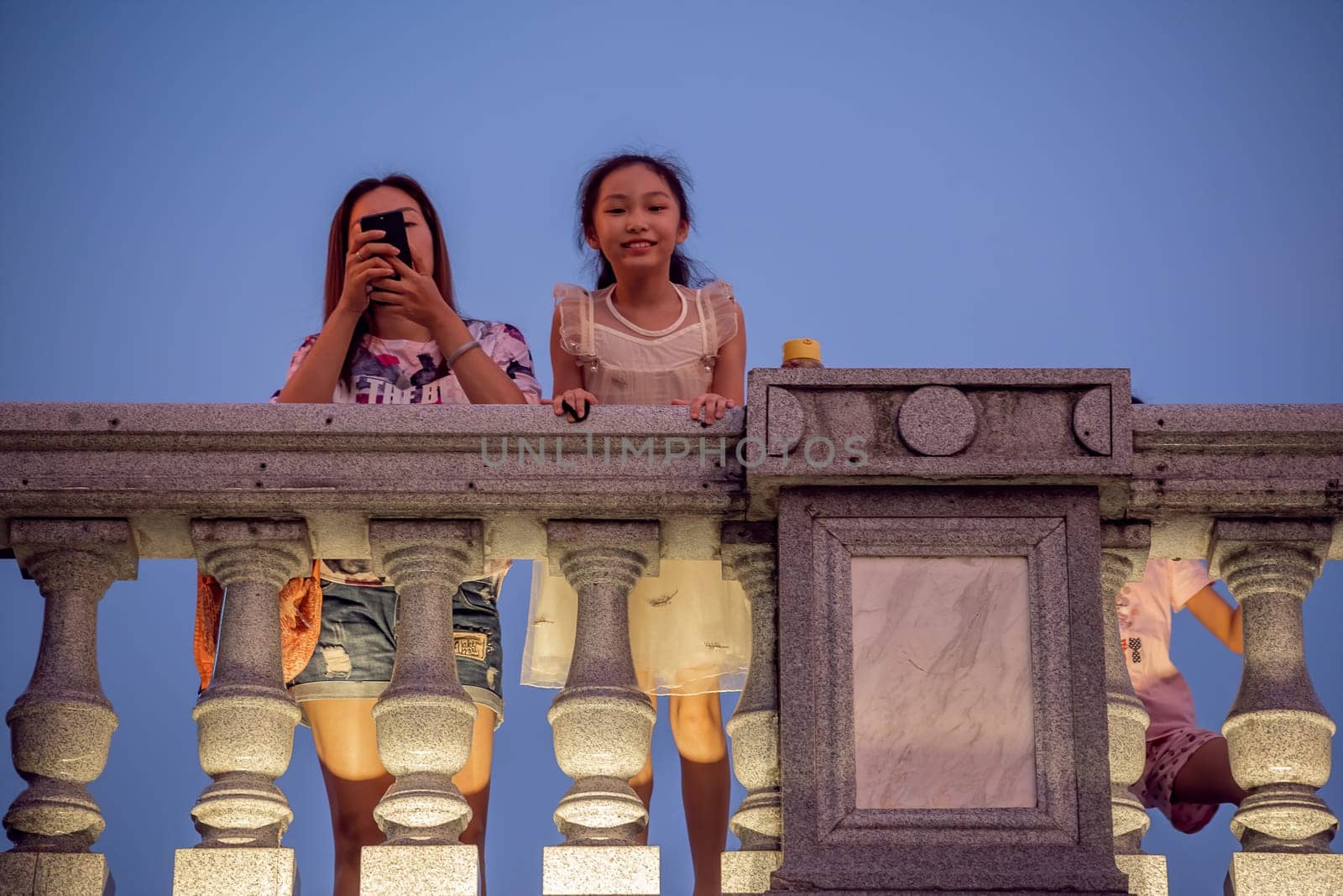 Guilin, China -  August 2019 : Mother with her children looking down from the road Bridge over the estuary of Rong and Shan Lakes at night, Guilin town, Guangxi Province