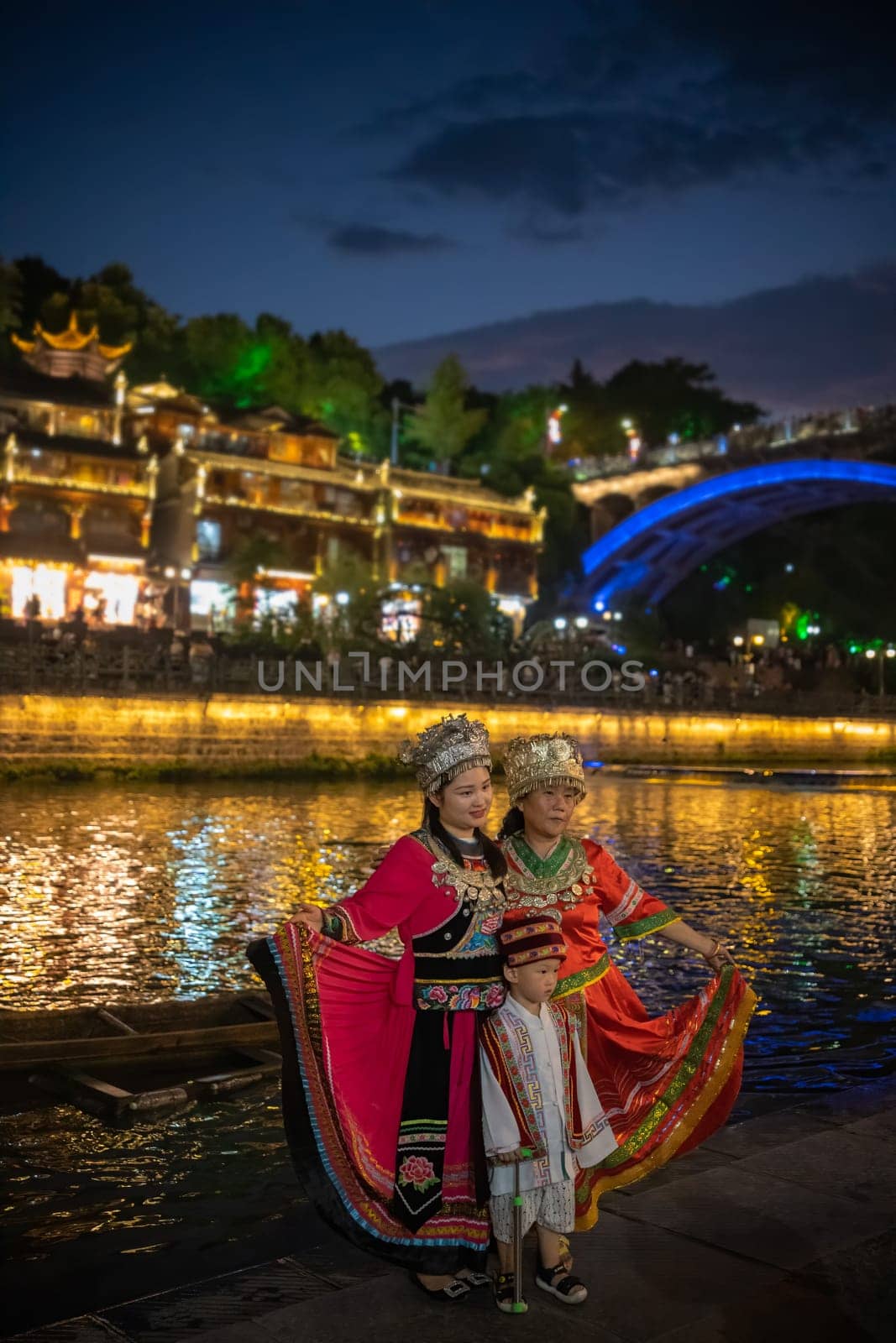 Feng Huang, China -  August 2019 : Chinese family female generations dressed in traditional folk costumes posing for a photo on the riverbank of Tuo river, flowing through the centre of Fenghuang Old Town