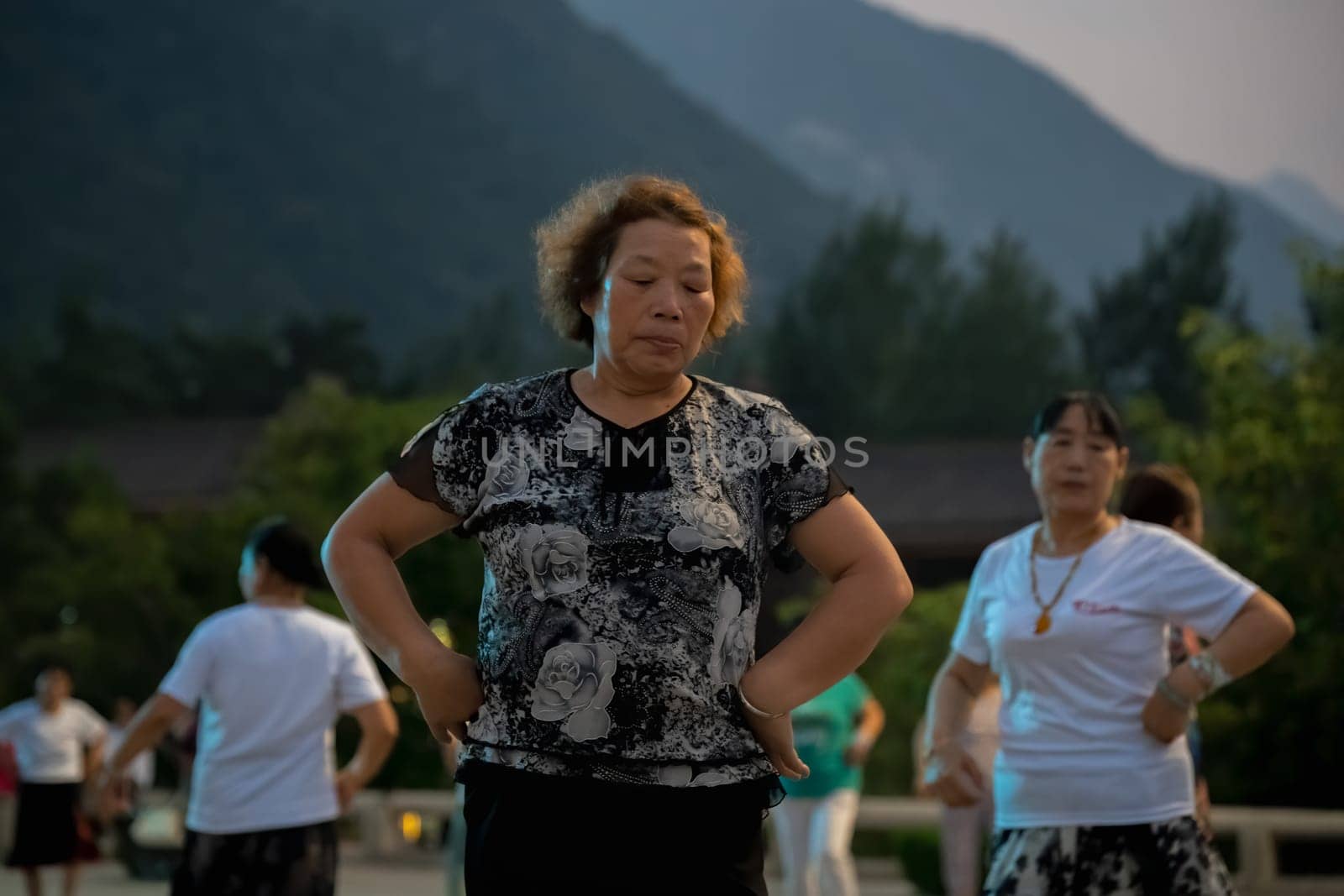 Huashan, China -  August 2019 : Group of Chinese women dancing in the open plaza square at the foot of HuaShan mountain at dusk, Shaanxi Province