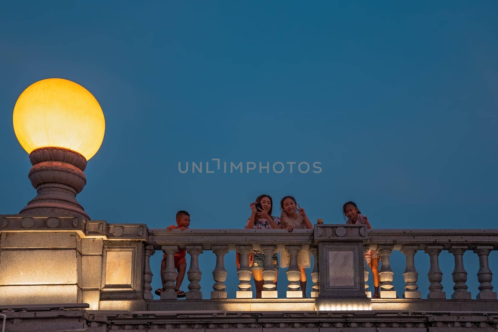 Guilin, China -  August 2019 : Mother with her children looking down from the road Bridge over the estuary of Rong and Shan Lakes at night, Guilin town, Guangxi Province
