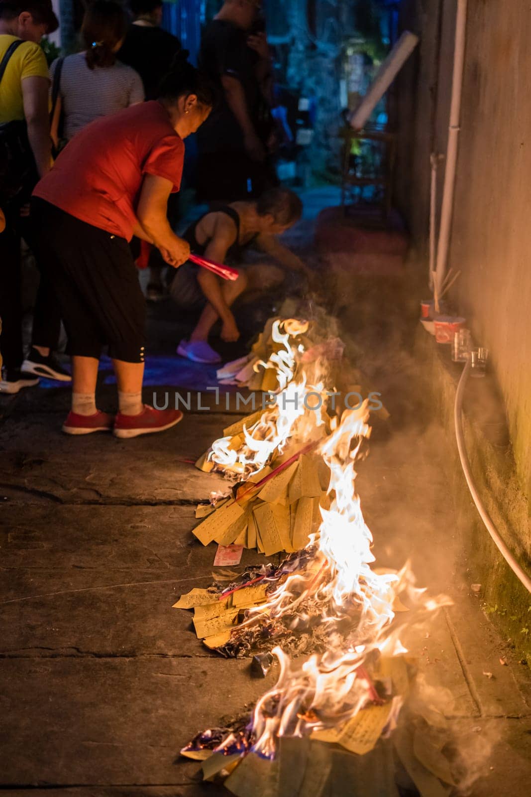Feng Huang, China -  August 2019 : People burning paper on streets and pavements in a religious festival ceremony to pay respect to ancestors and spirits