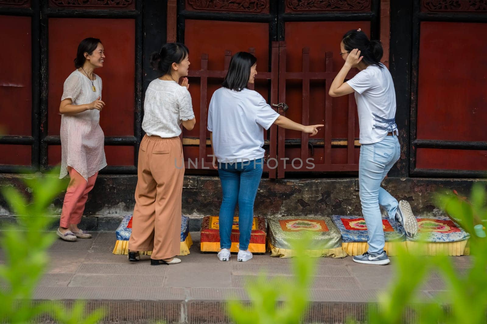 Chengdu, China -  July 2019 :  Four women preparing for a prayer in front of colorful praying kneeling pads in the courtyard of the Buddhist Wenshu Monastery, Sichuan Province