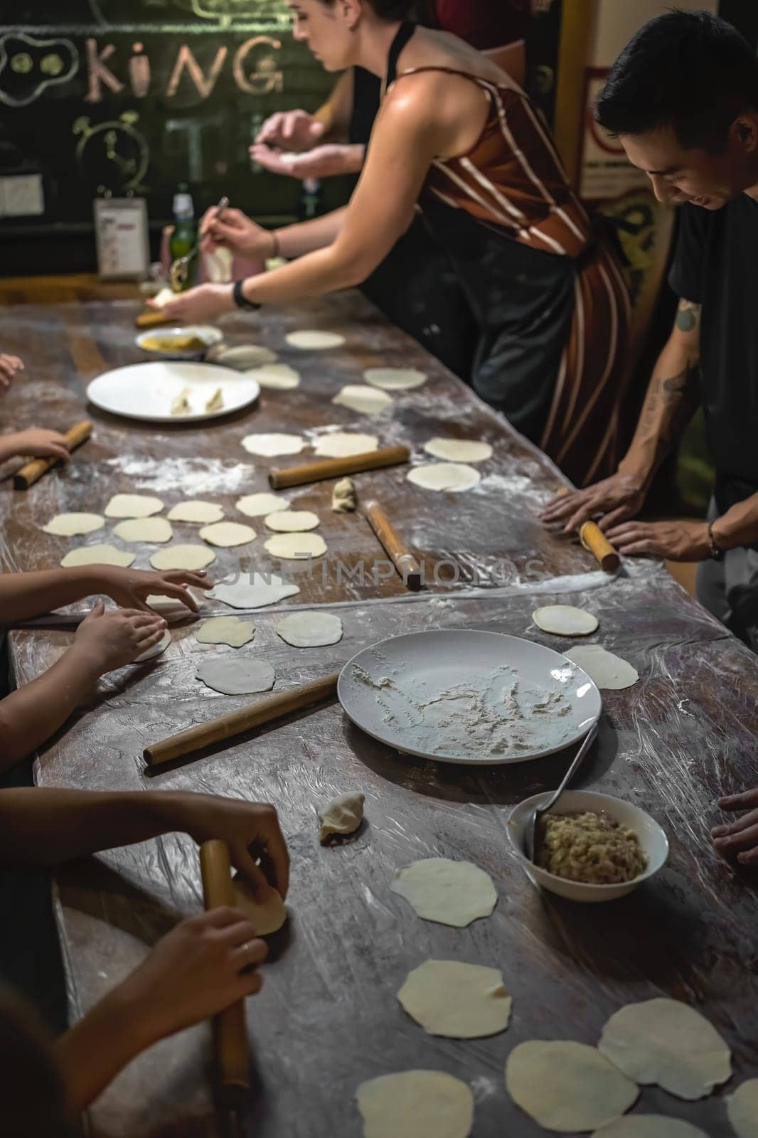 Chengdu, China -  July 2019 : People learning the art of making of traditional chinese dumplings during cooking class in a travellers hostel