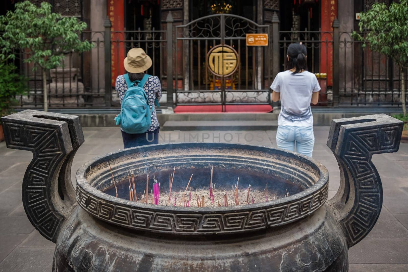 Chengdu, China -  July 2019 : Chinese woman and man praying, worshiping, burning incense sticks, giving alms and thanks at the Wenshu Chinese Buddhist Temple