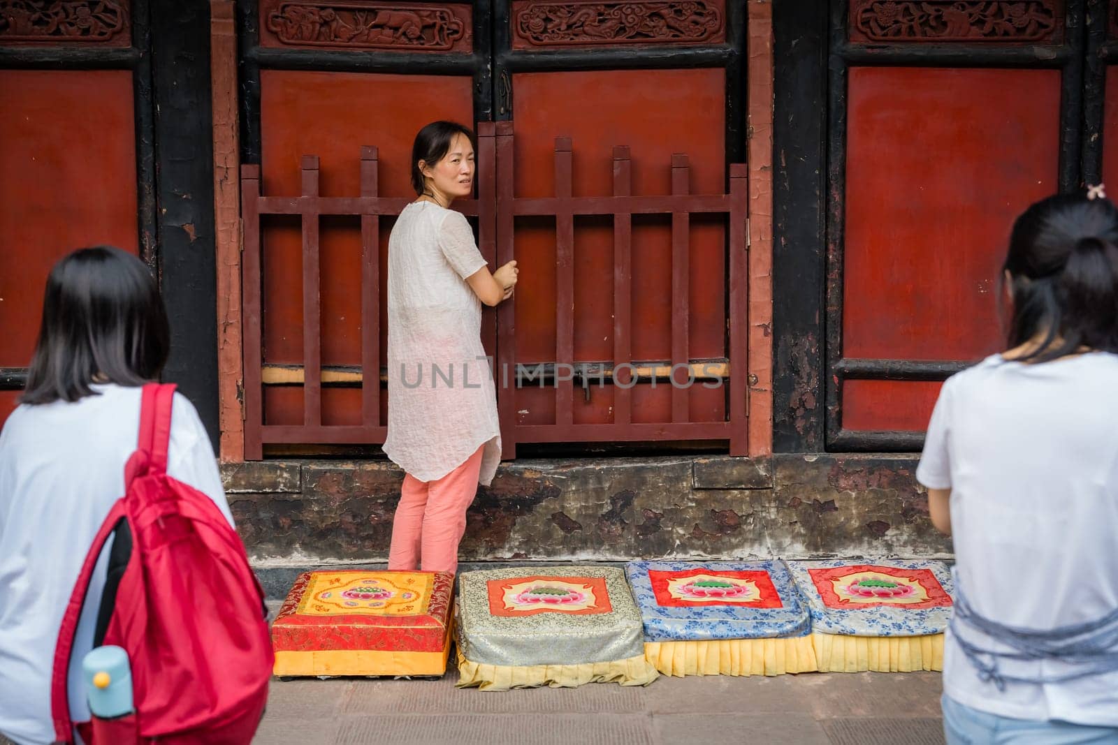 Chengdu, China -  July 2019 :  Chinese woman preparing for a prayer in front of colorful praying kneeling pads in the courtyard of the Buddhist Wenshu Monastery, Sichuan Province