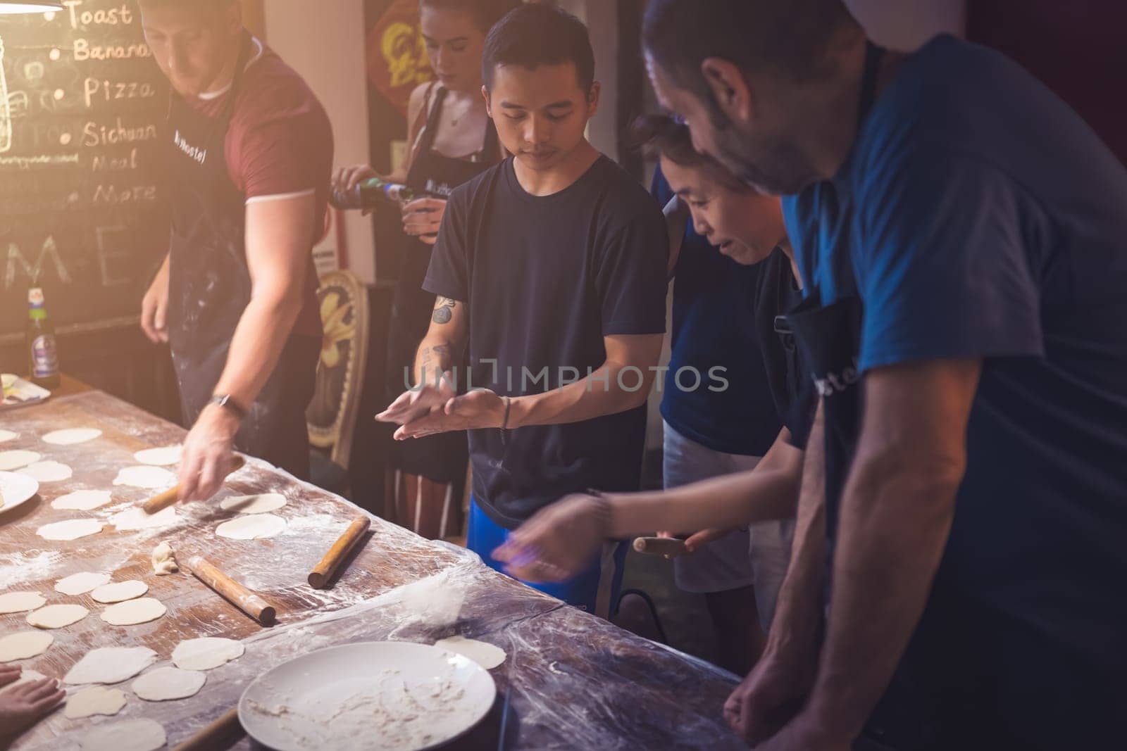 Chengdu, China -  July 2019 : People learning the art of making of traditional chinese dumplings during cooking class in a travellers hostel