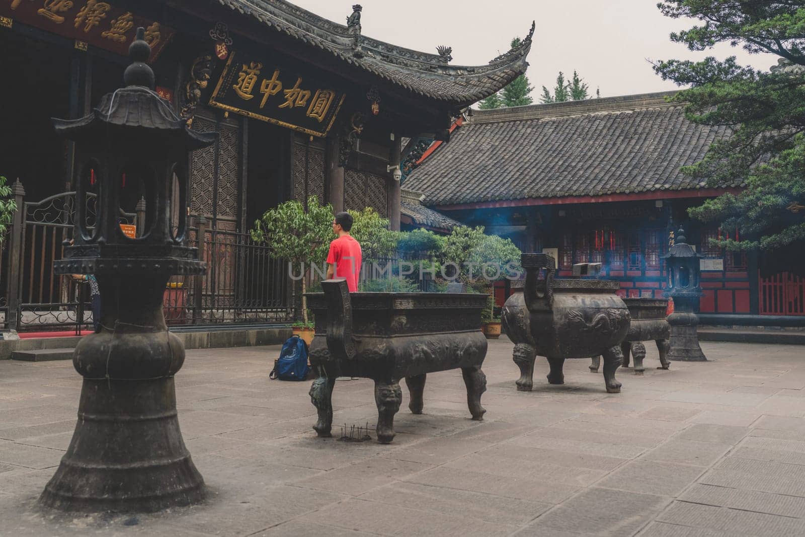 Chengdu, China - July 2019 : Chinese person praying, worshiping, burning incense sticks, giving alms and thanks at the Wenshu Chinese Buddhist Temple