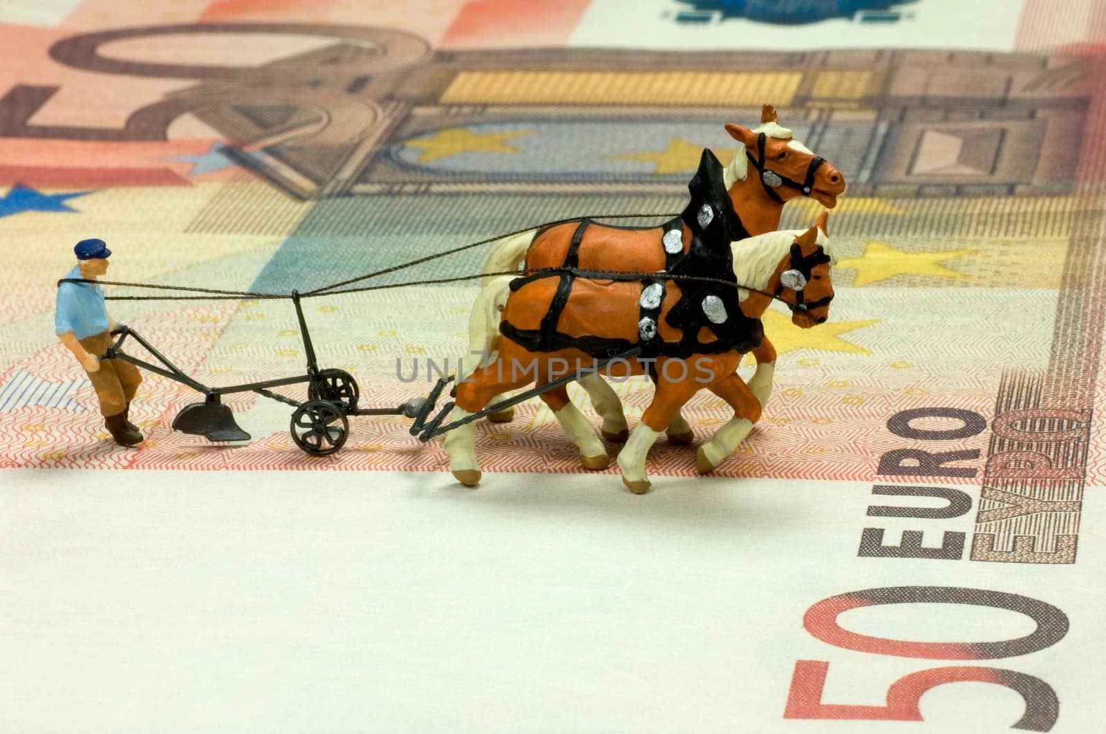 Miniature figure of a ploughman with two horses on a fifty Euro bill. With space for copy.