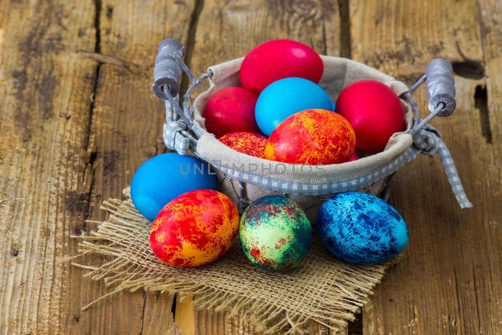 Happy Easter, colorful eggs in a basket on wooden background
