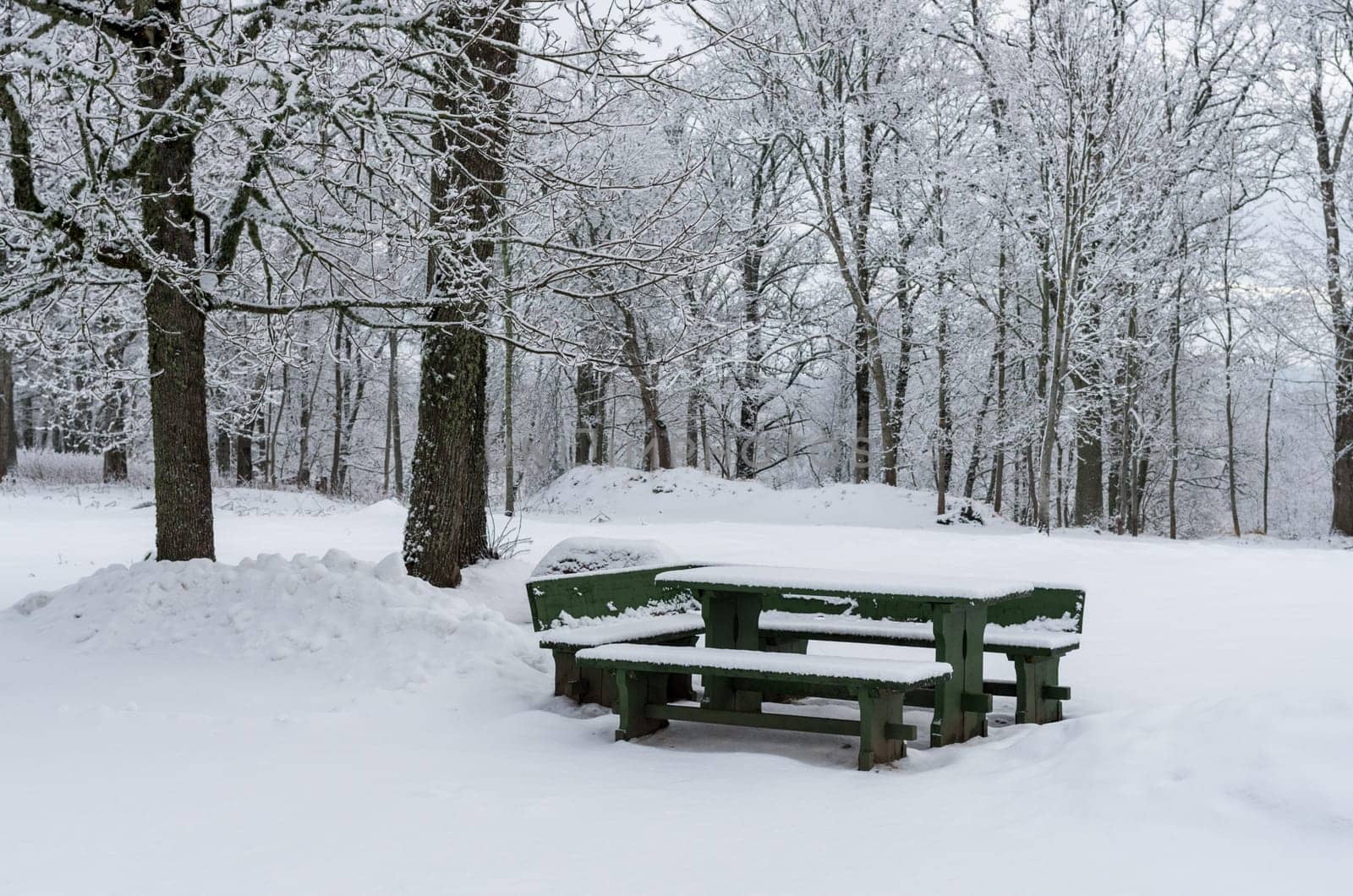 Wooden picnic table with benches after heavy snowfall