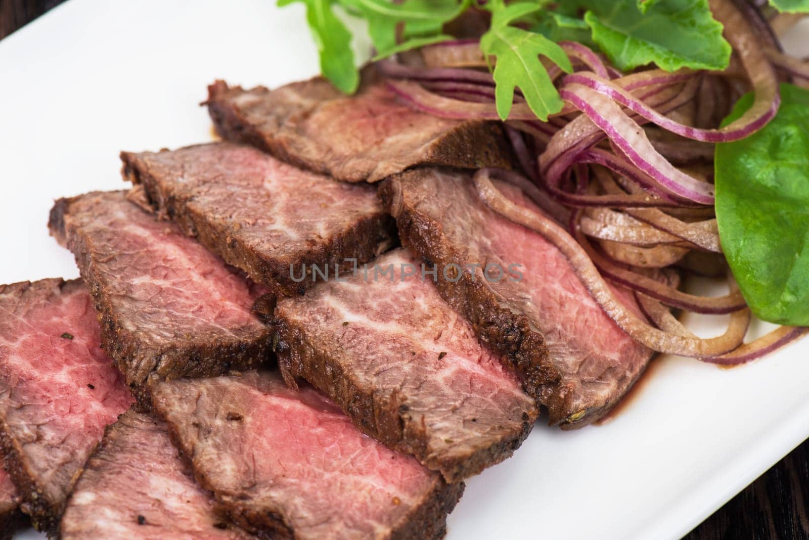 Plate with meat cutting and fresh greens on white plate