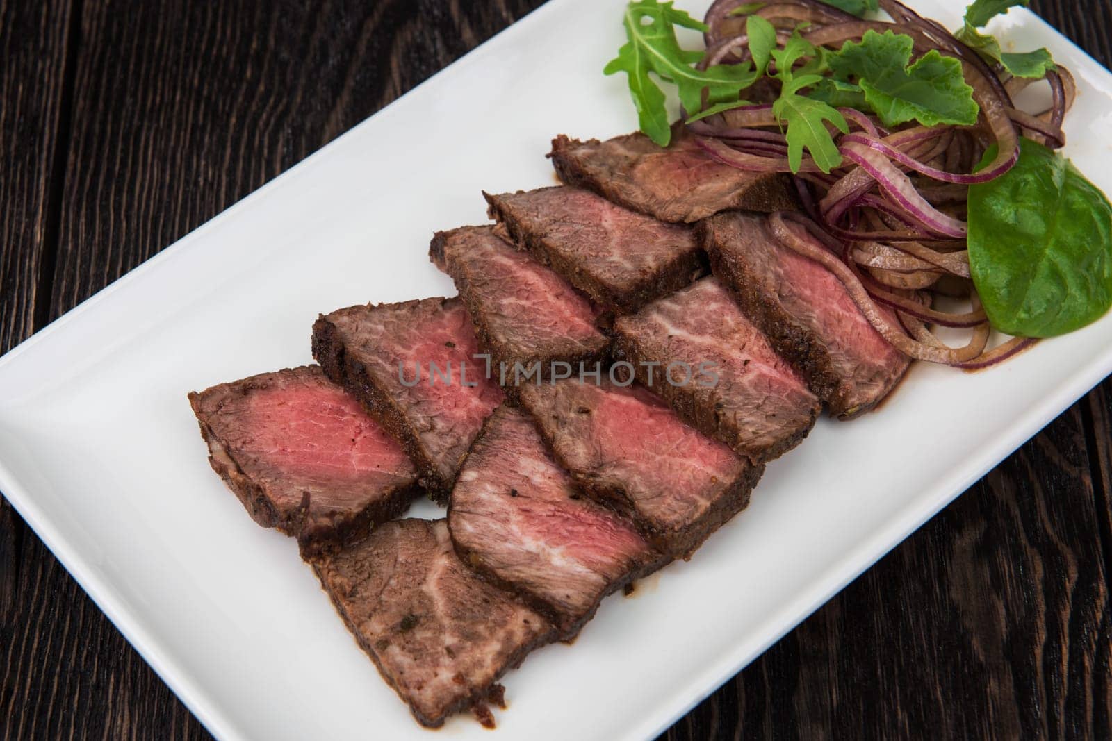 Plate with meat cutting and fresh greens on white plate