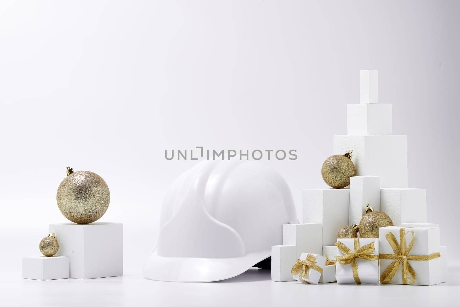 Construction hard hat, white fir tree, gift boxes and Christmas ornament on a white background with copy space. New Year and Christmas construction background