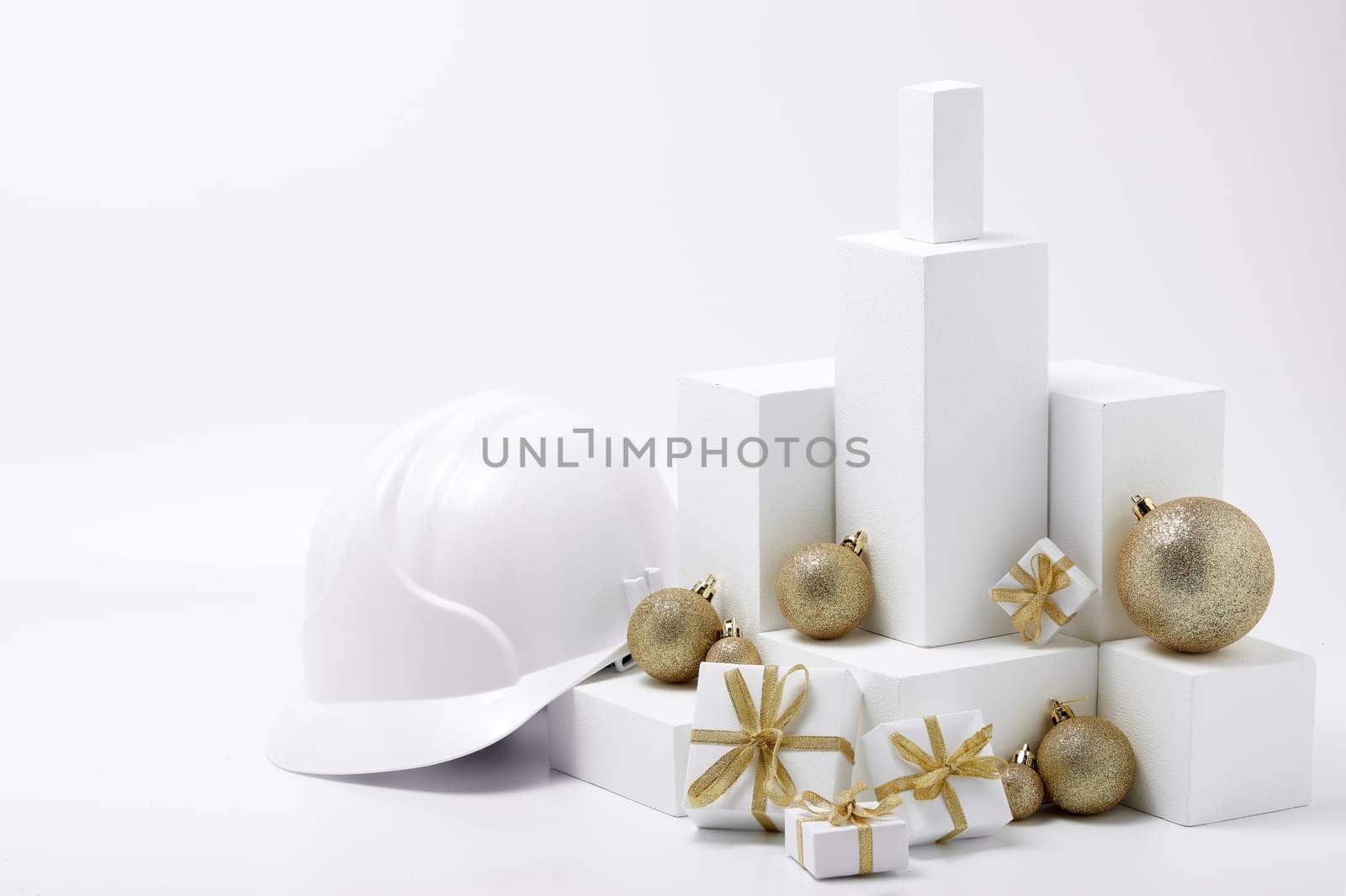 Construction hard hat, white fir tree, gift boxes and Christmas ornament on a white background with copy space. New Year and Christmas construction background