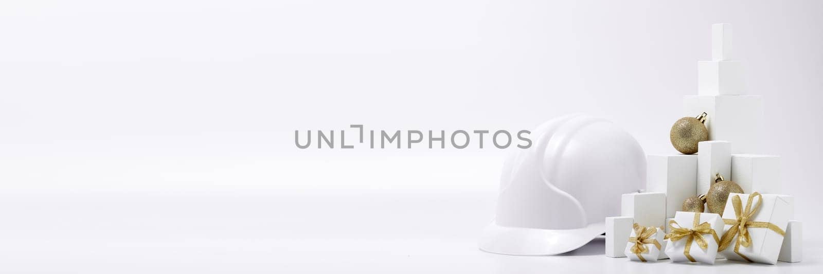 Construction hard hat, white fir tree, gift boxes and Christmas ornament on a white background with copy space. New Year and Christmas construction background