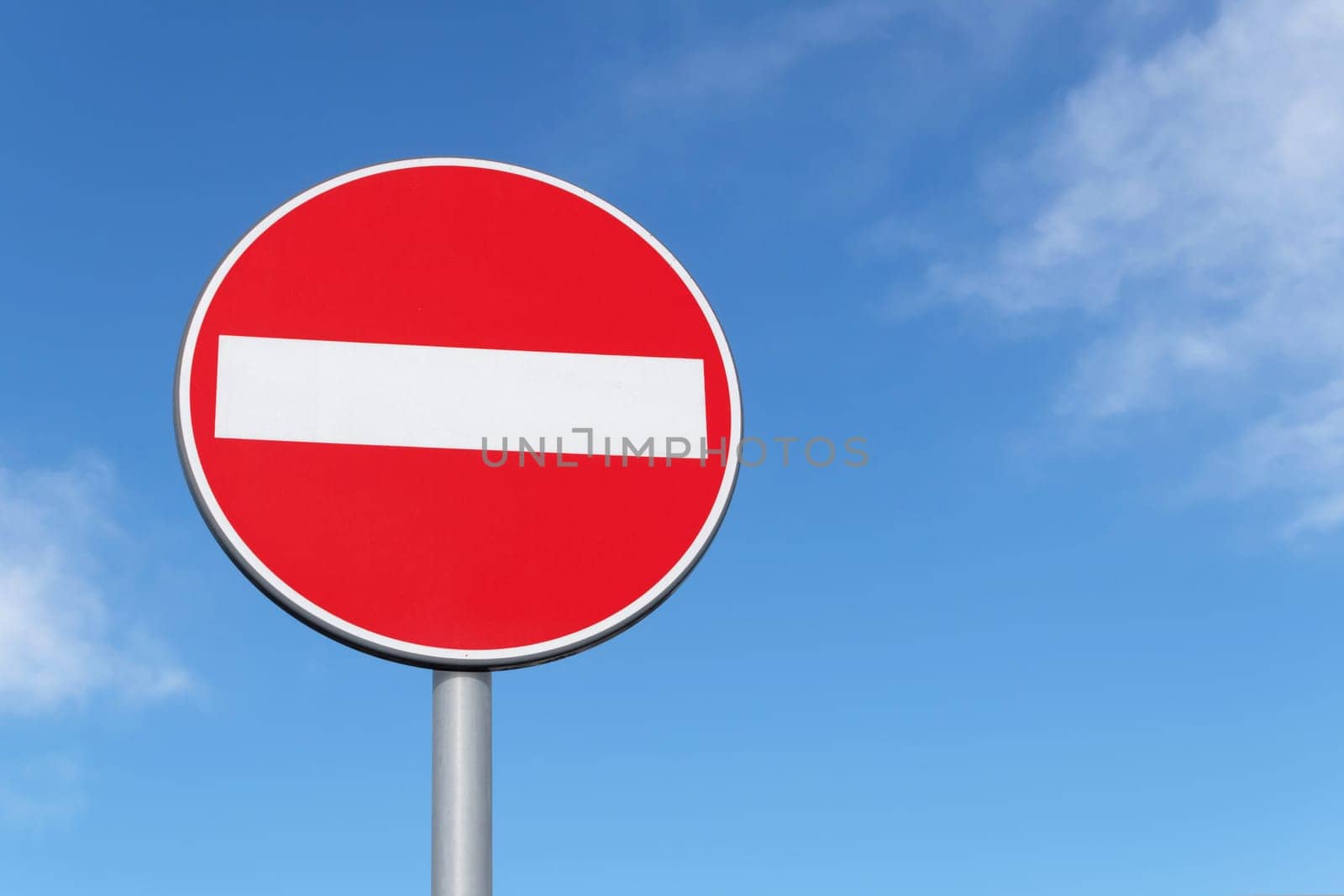 Red and white no entry traffic sign on a blue sky background