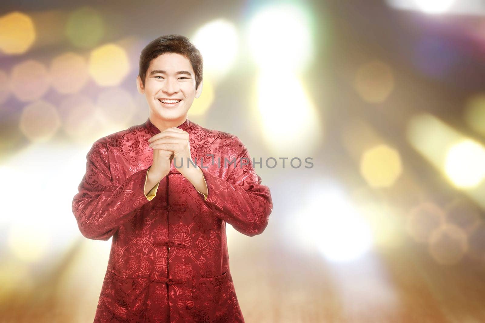 An Asian Chinese man in a cheongsam dress with congratulations gesture. Happy Chinese New Year